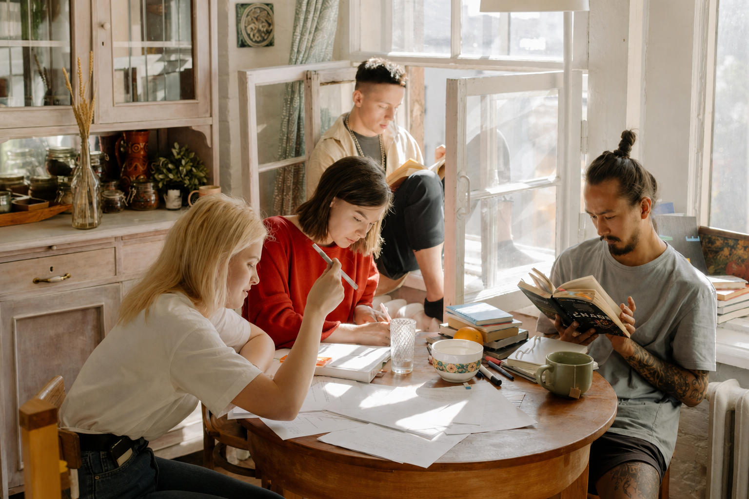 Four people reading and working together around a table